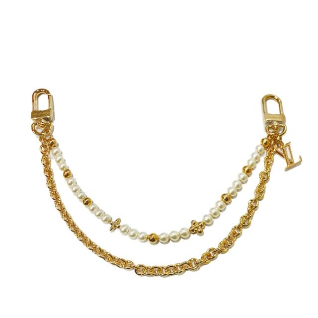 LV LOUIS VUITTON路易威登 M02608 經典 Pearl River 系列金屬花卉圖案白色珍珠包包吊飾 經典素色時尚風格,高貴典雅的設計,完美融合流行時尚與優雅品味。這款白色珍珠包包吊飾以金屬花卉圖案為特色,適合搭配各種風格的包包,增添貴氣與獨特魅力。LV LOUIS VUITTON 經典 Pearl River 系列,展現品牌精湛工藝與時尚感。